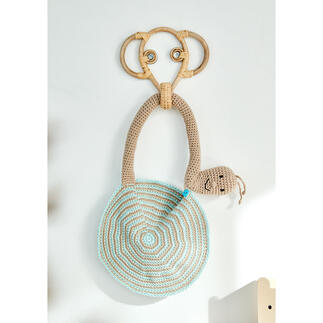 Schlabberlatz in Schneckenform aus Cotonia II, an einer Wand aufgehängt.