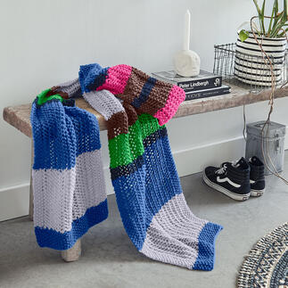 Bunte Strickschals aus NewWool auf einer rustikalen Bank.