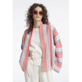 Frau in einer bunten gehäkelten Jacke mit Sonnenbrille, posiert in heller Raum.