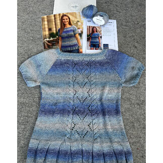 Pullover aus Pinterella in Blau- und Lilatönen, Zubehör und Anleitung auf einem Tisch.