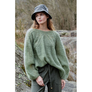 Grüner Pullover aus Ingenua, Modell mit Hut im Freien.