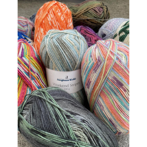 Bunte Wundertüte mit verschiedenen Sockengarnen auf einem grauen Hintergrund.