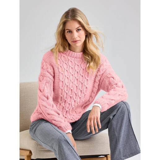 Frau in rosa Pullover aus Canoso, sitzt lässig auf einem Stuhl