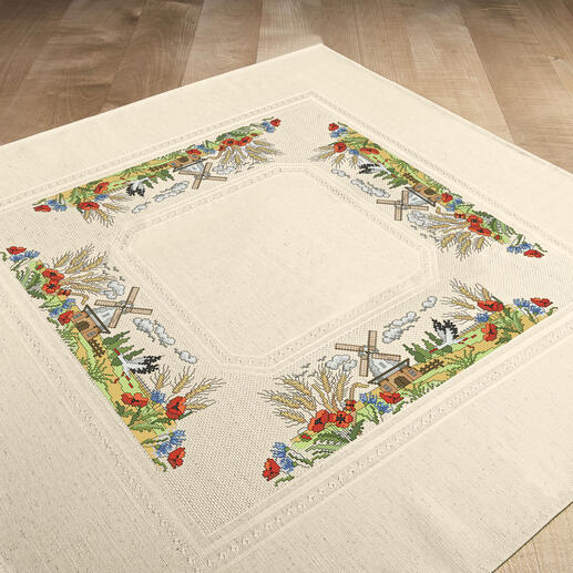 Tischdecke mit einem Mühlen-Motiv und bunten Blumen auf einem Boden.