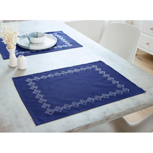 Zwei dunkelblaue Platzdeckchen mit geometrischem Muster auf einem Tisch.
