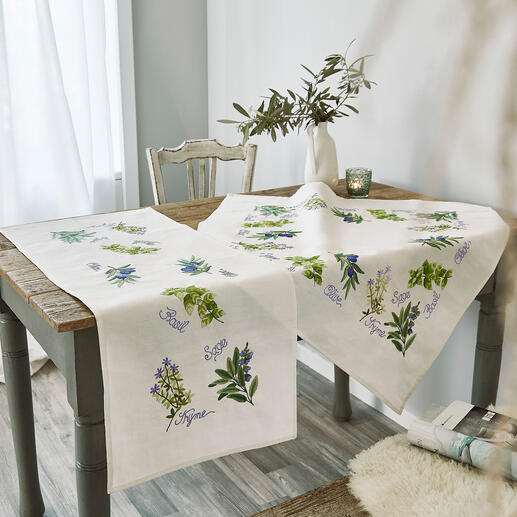 Tischwäsche mit bunten Küchenkräutern und dekorativen Schriftzügen auf hellem Hintergrund.