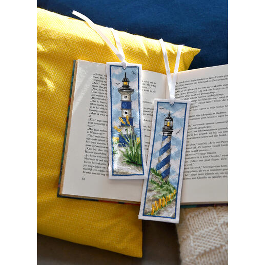 Zwei Lesezeichen mit Leuchttürmen auf einem offenen Buch.