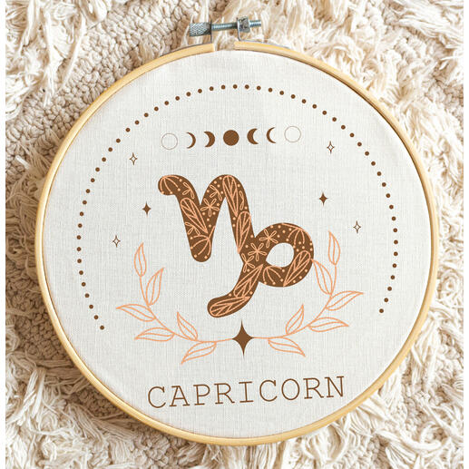 Minimalistische Stickerei des Sternzeichens Steinbock mit floralen Motiven.