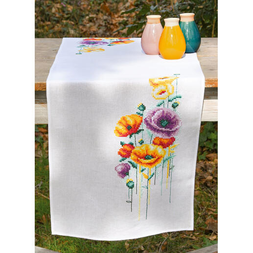 Tischläufer mit Mohnblumen, bunten Vasen und entblößtem Tisch.