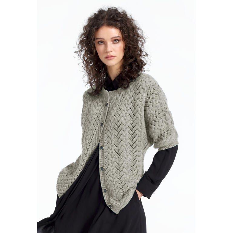 Frau in einer grauen Jacke aus Babyboomer, lächelnd, in schwarzem Kleid