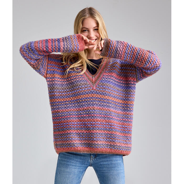 Frau in einem bunten Pullover aus Batique, spielt und lächelt