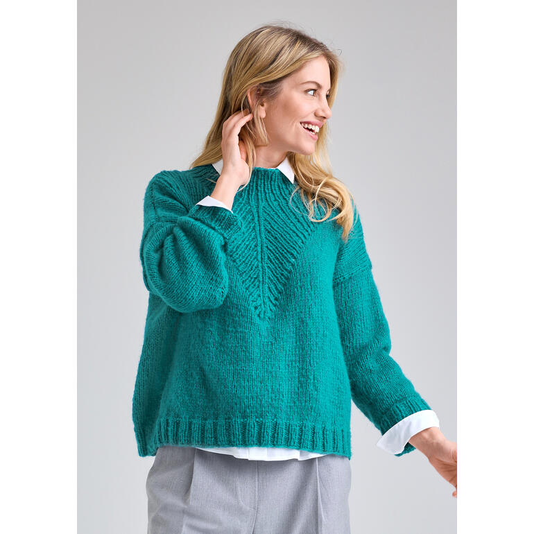 Frau in einem grünen Pullover aus NewWool, lächelnd und fröhlich