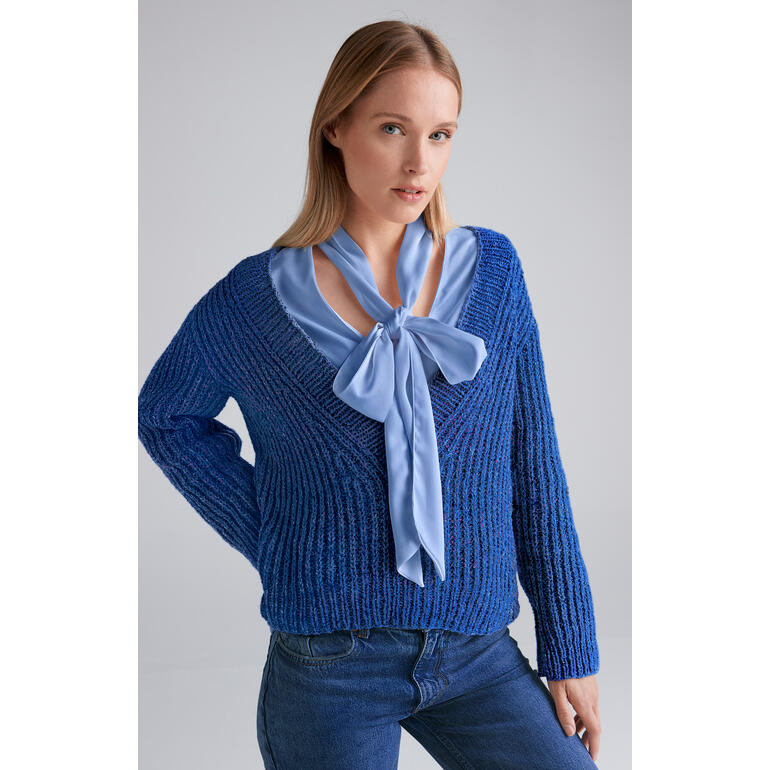 Blauer Pullover aus Punktino, weibliches Model mit Schleife am Hals.