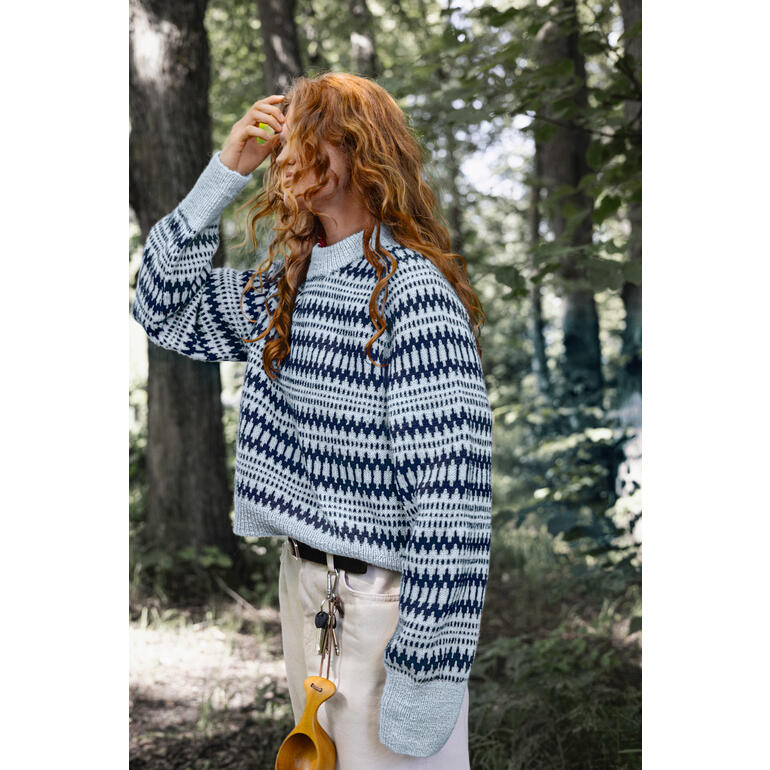 Frau in gestreiftem Pullover aus Tynn Peer Gynt, steht im Wald.