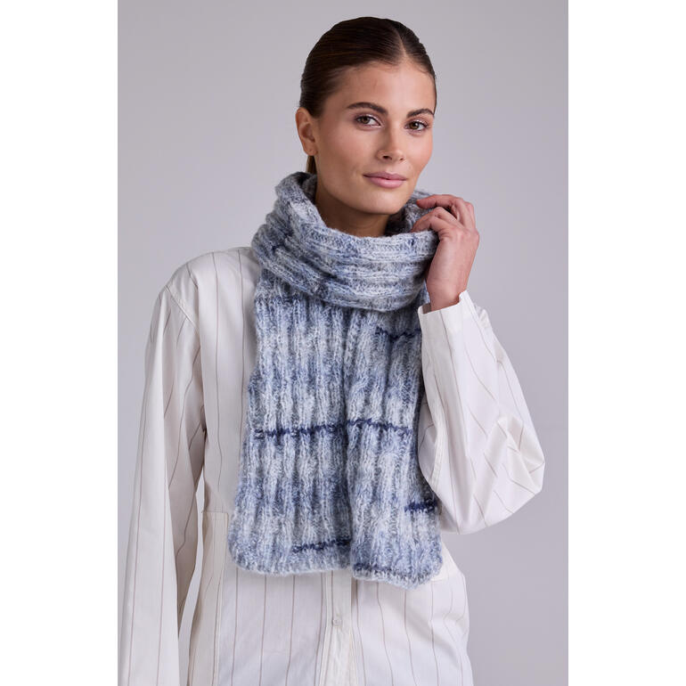 Dame mit blauem Schal aus Stoccolma von Junghans-Wolle lächelt in modischem Outfit.