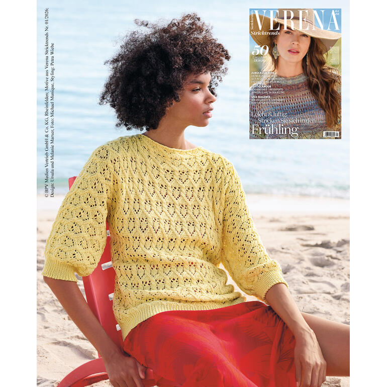Frau trägt einen gelben Pullover am Strand, Zeitschrift im Hintergrund