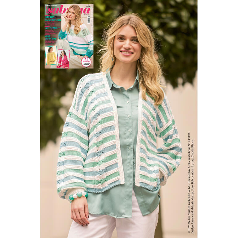 Frau in Ajour-Strickjacke, leicht lächelnd, vor grünem Hintergrund.