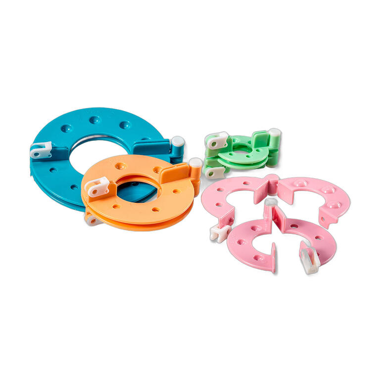 Pompon-Maker in verschiedenen Größen und Farben, verstreut auf weißem Hintergrund.