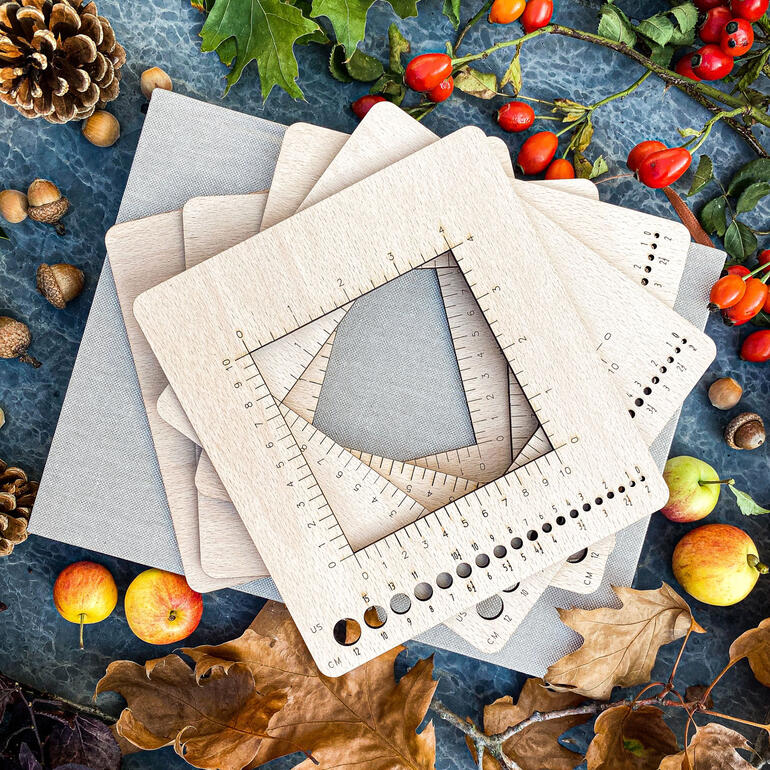 Mehrere Nadelmaß-Rahmen auf einer Unterlage aus Naturmaterialien.