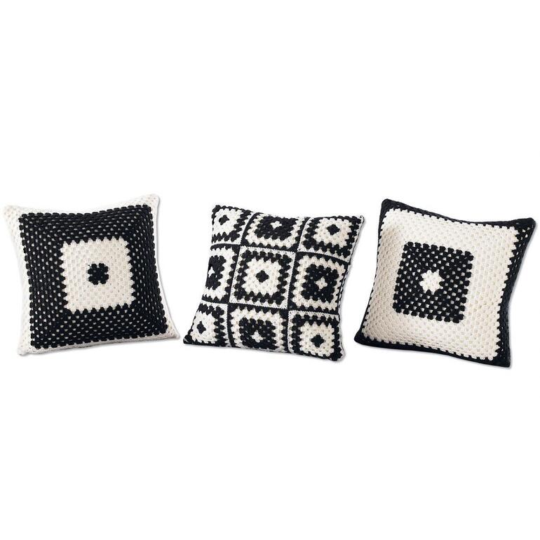 Drei gehäkelte Kissenhüllen in Schwarz und Weiß mit verschiedenen Mustern.