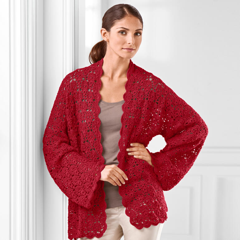 Häkeljacke in kräftigem Rot, aus vielen Rechtecken, eine Frau posiert dafür.