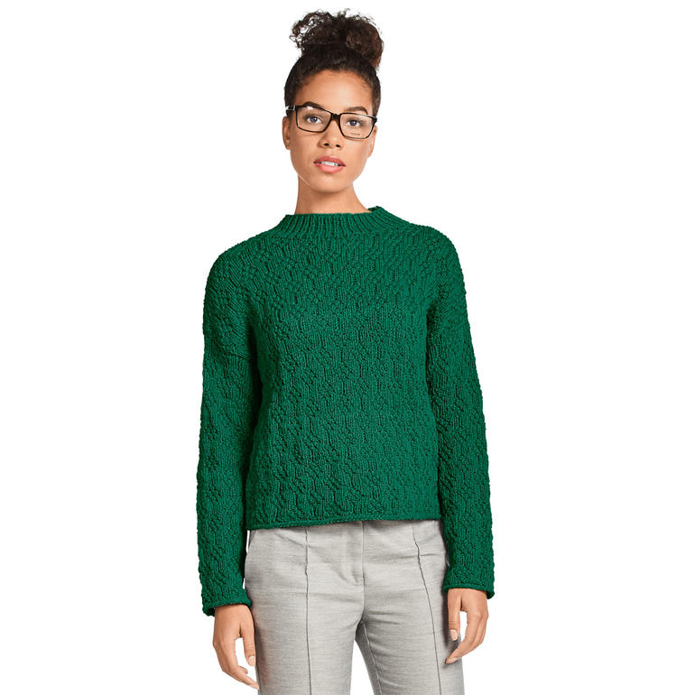 Dame in grünem Damenpullover, blickt ernsthaft zur Seite.