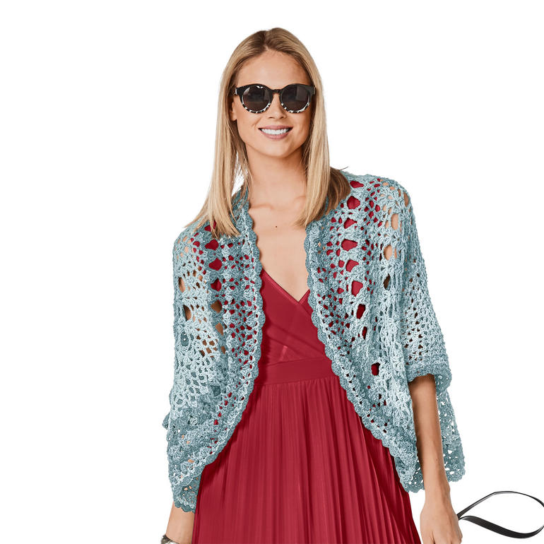 Frau in hellblauem Bolero aus Pinta, trägt Sonnenbrille, vor neutralem Hintergrund.