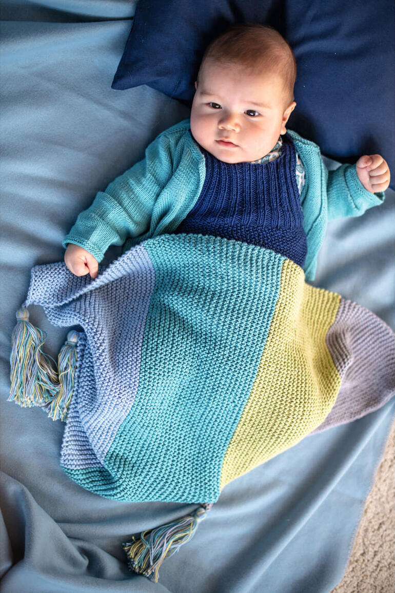 Baby in einer bunten Decke aus Baby Smiles Cotton Bamboo.