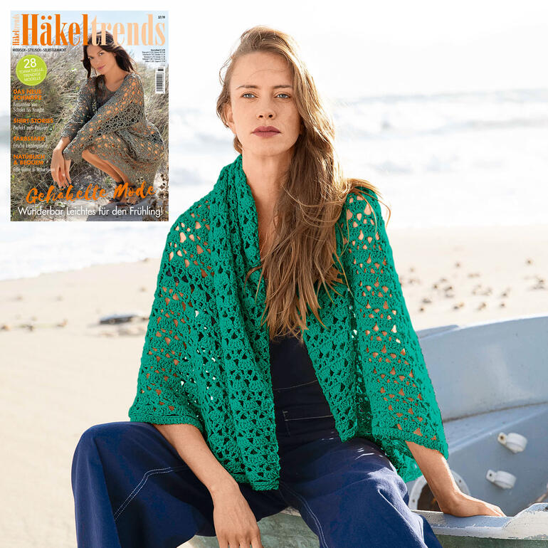 Dame in grüner Häkeljacke aus Cotonara mit Modemagazin am Strand.
