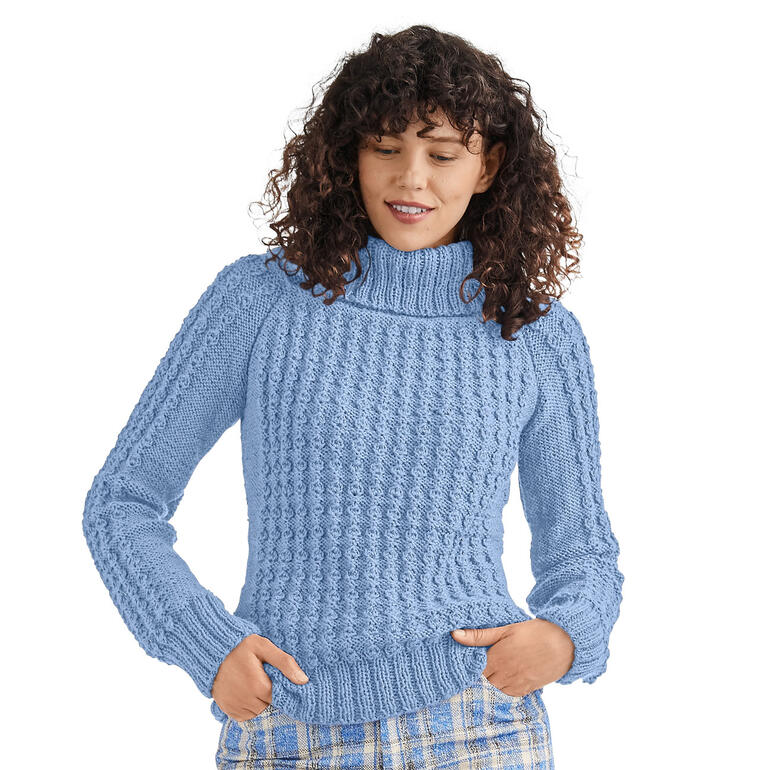 Frau steht in hellblauem Pullover aus Peru von Junghans-Wolle und zeigt die Struktur.