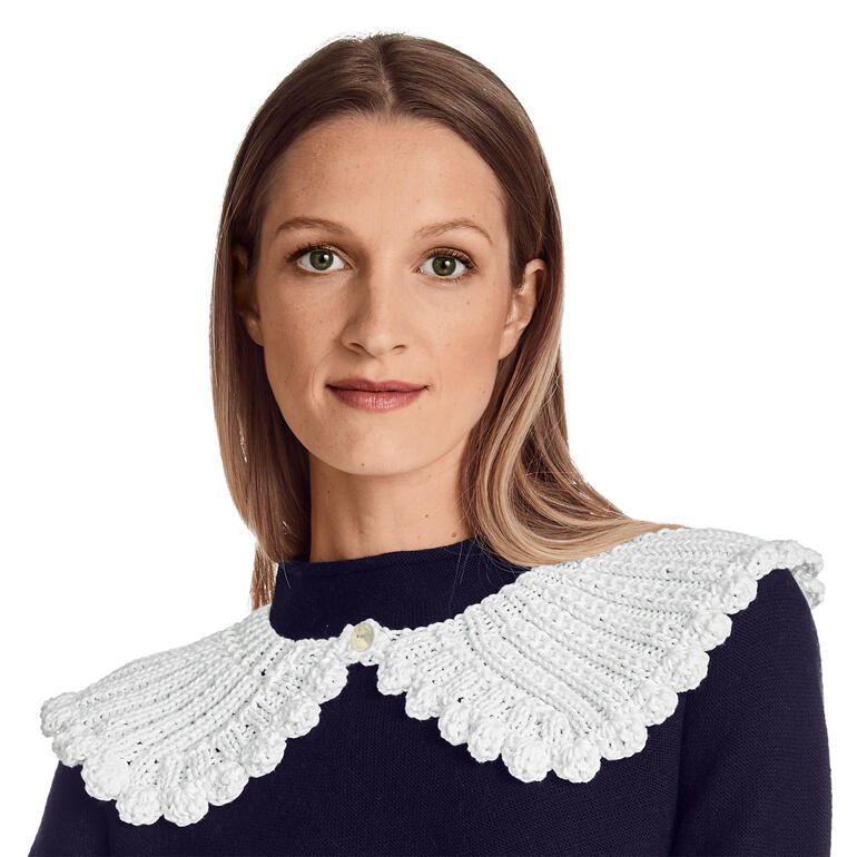 Weißer Häkelkragen, detailreich, von Frau mit schwarzem Oberteil getragen.