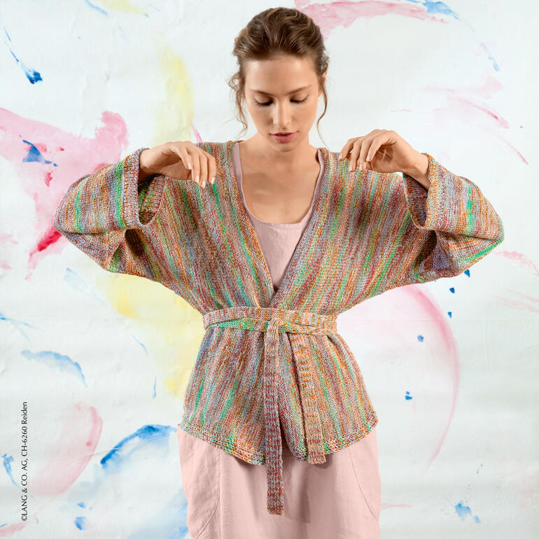 Bunte Jacke aus Karma, getragen von einer Frau vor einem farbenfrohen Hintergrund.