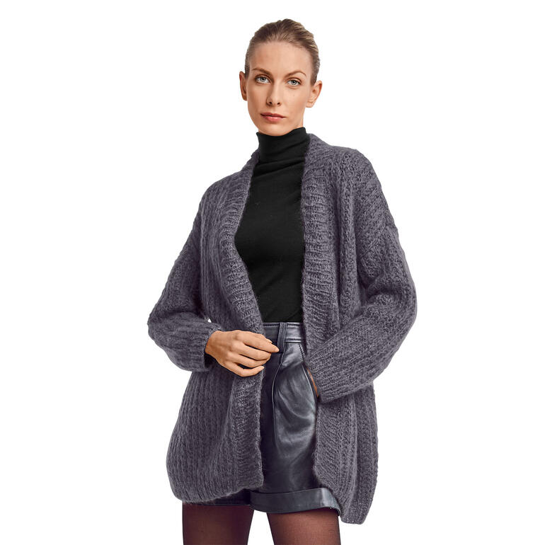 Frau trägt eine graue Jacke aus Feelana, kombiniert mit einem schwarzen Rollkragenpullover.