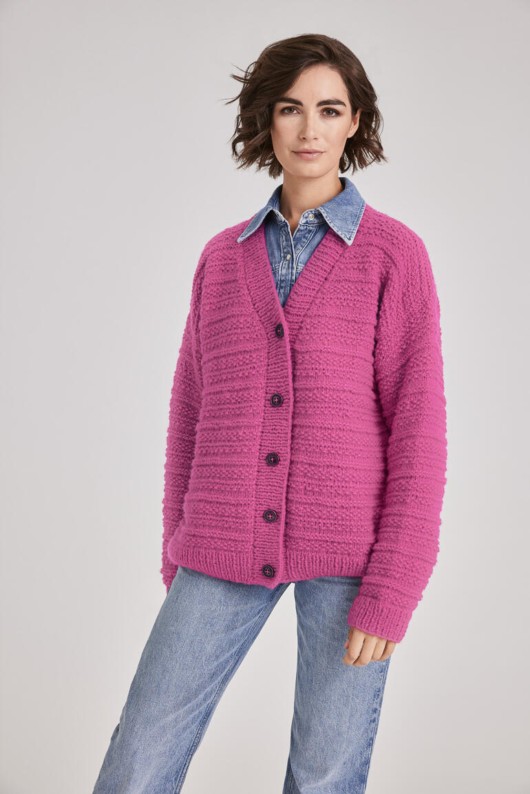 Frau in pinker Jacke mit Knöpfen lächelt lässig, zeigt Vorderansicht.