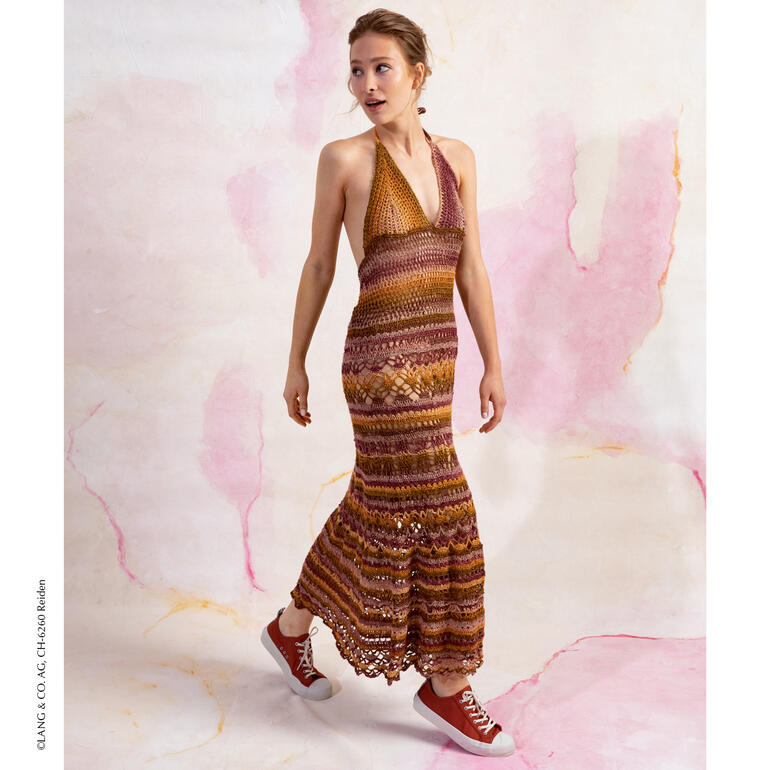 Sichnderes Häkelkleid in warmen Erdtönen an einer Model mit Sneakern.