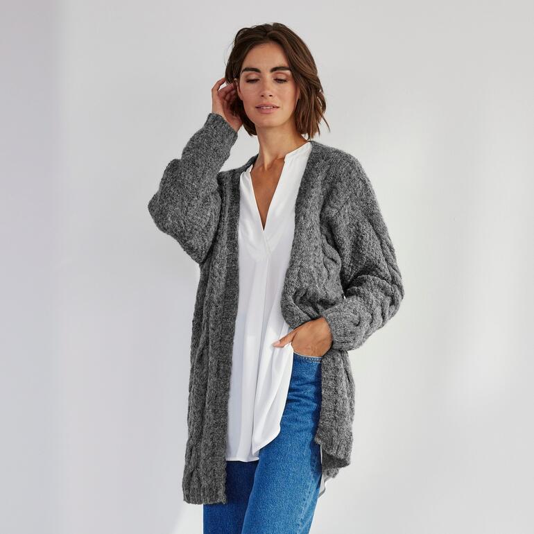 Frau in grauer Strickjacke vor minimalistischem Hintergrund