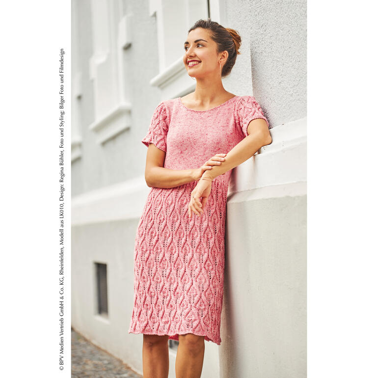 Kleid aus Viva Summer in sanften Rosatönen, lächelnde Frau an einer Wand.