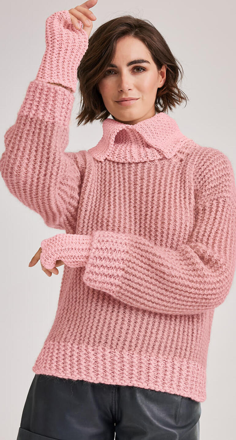 Frau in einem rosa Pullover mit separatem Kragen und Armstulpen.