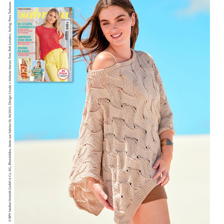 Frau trägt einen beigen Poncho aus recyclebarem Material am Strand