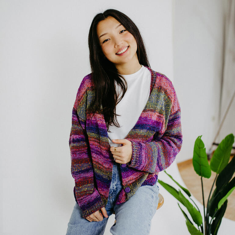 Frau trägt eine farbenfrohe Jacke aus Streifenwolle mit lächelndem Gesicht