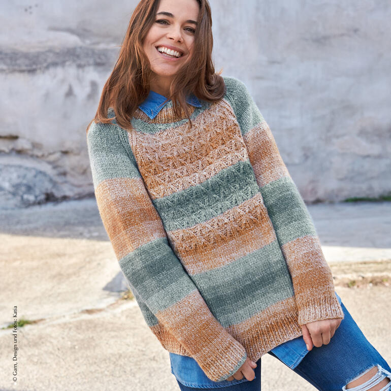Frau trägt einen gestreiften Pullover aus Cashmina Cotton, lächelt vor einer Wand.