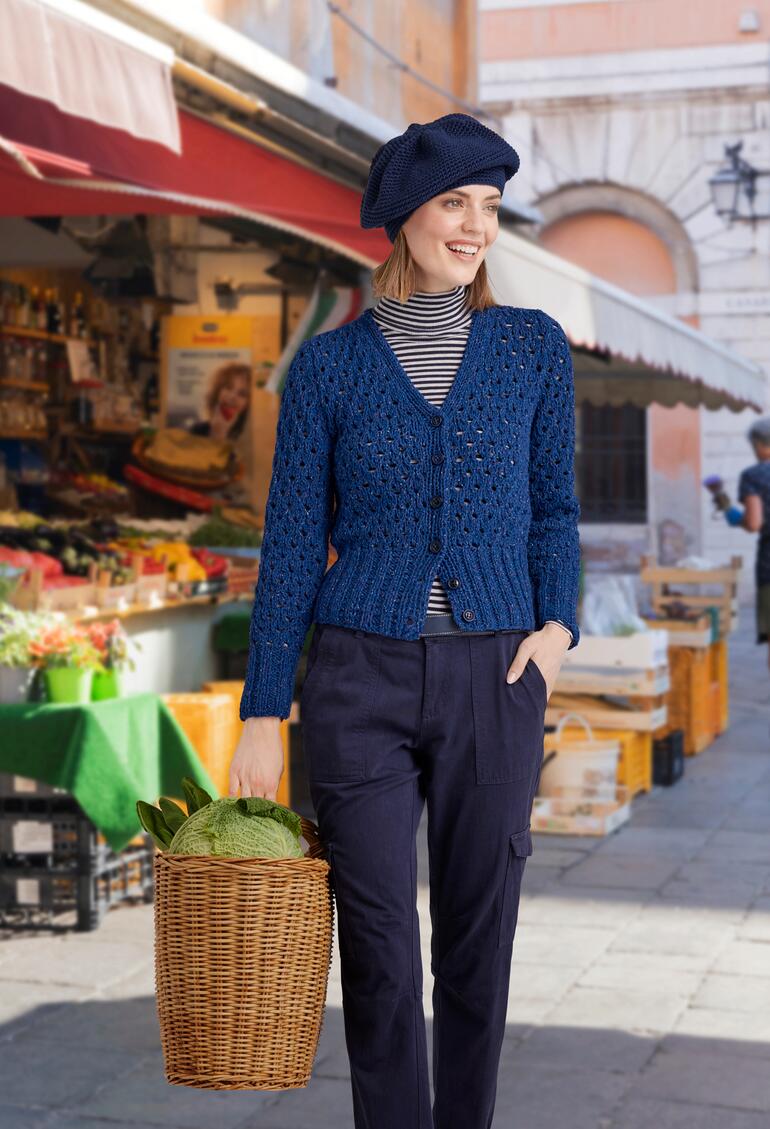 Frau in blauer Jacke aus Punktino mit Korb in einem Marktumfeld.