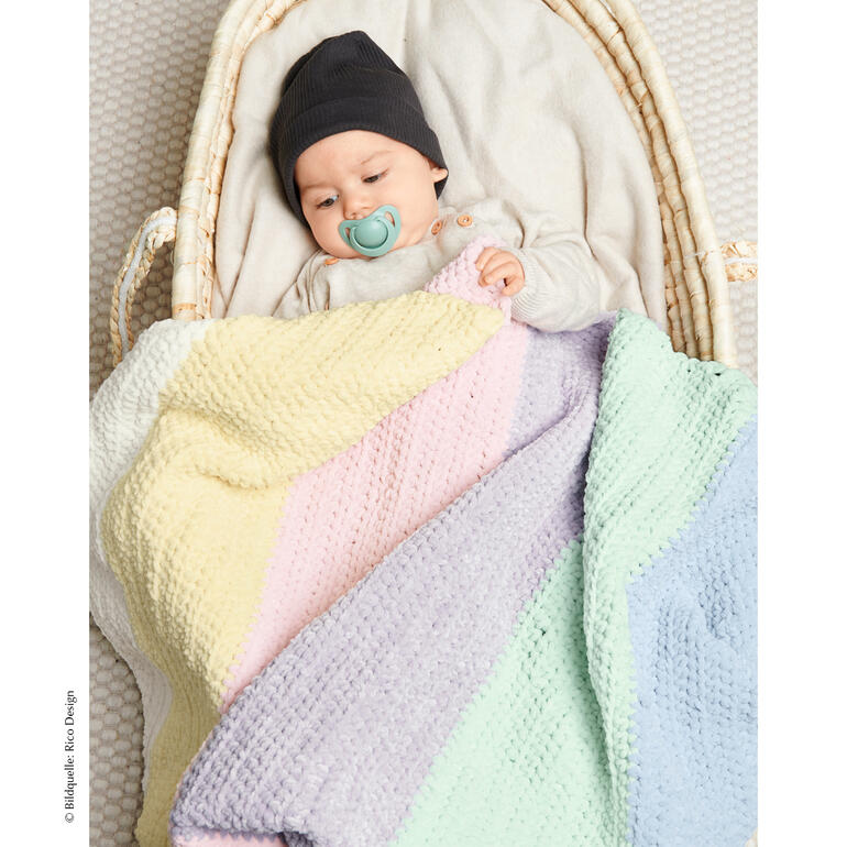 Baby liegt unter einer bunten gestreiften Decke und schläft.