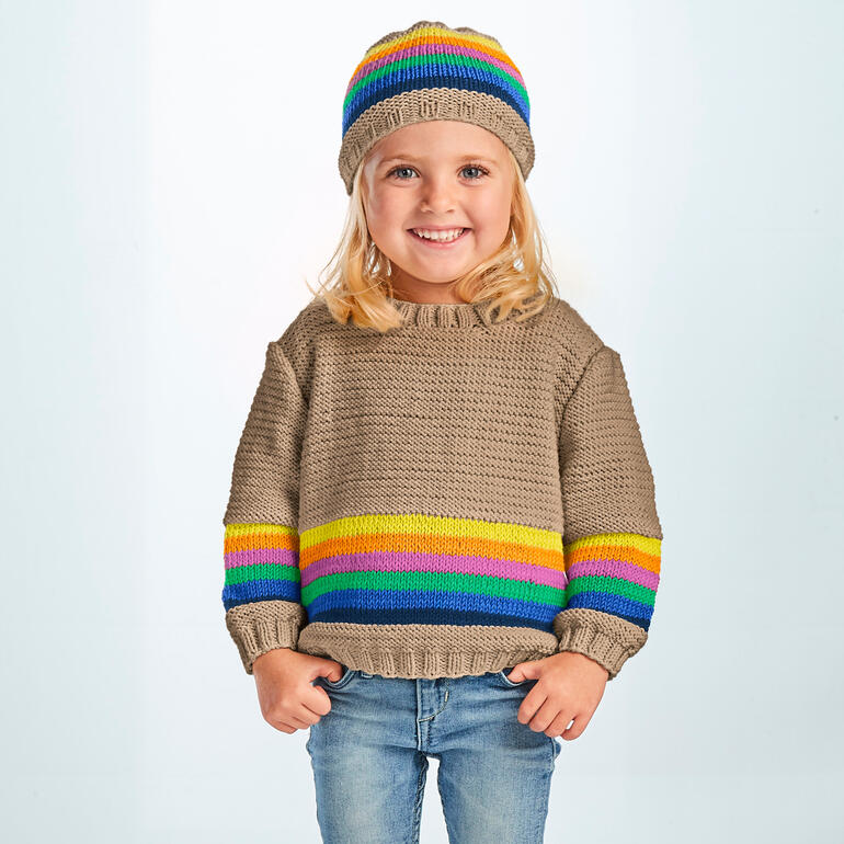 Kind trägt einen beige Pullover und eine farbige Mütze, lächelt in die Kamera.