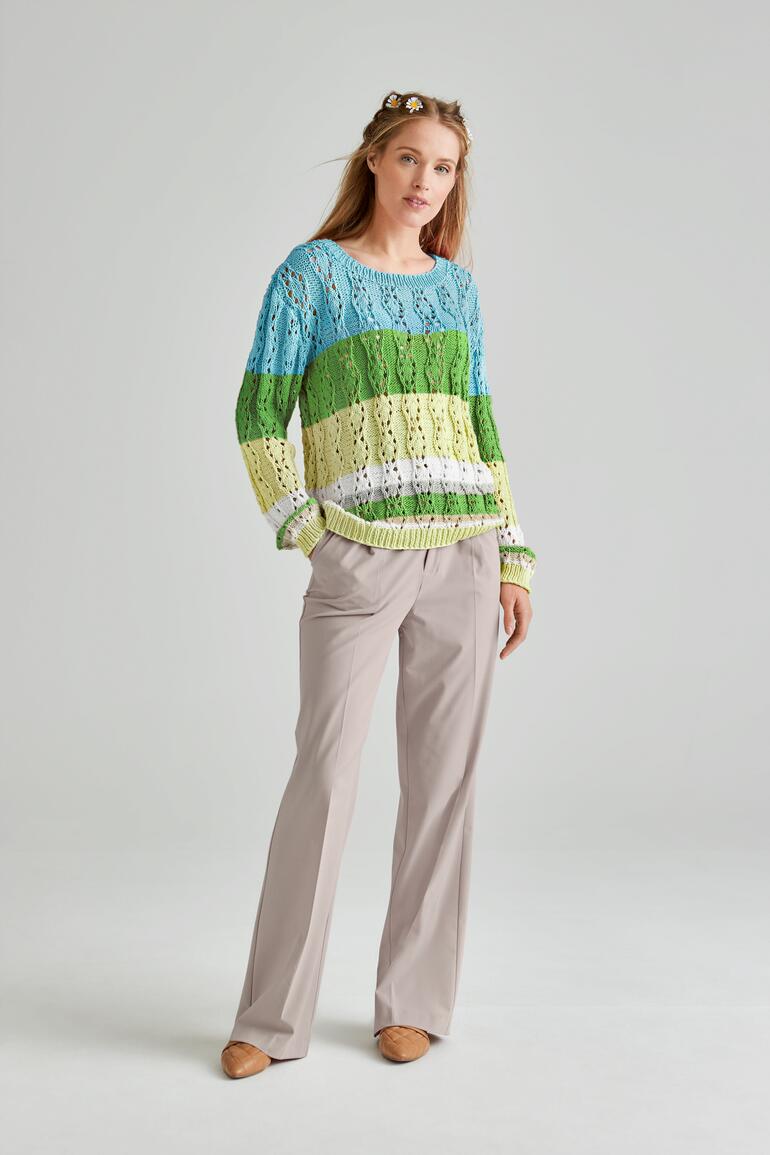 Frau trägt bunten Pullover aus Recycle & Cotone mit beigen Hosen.