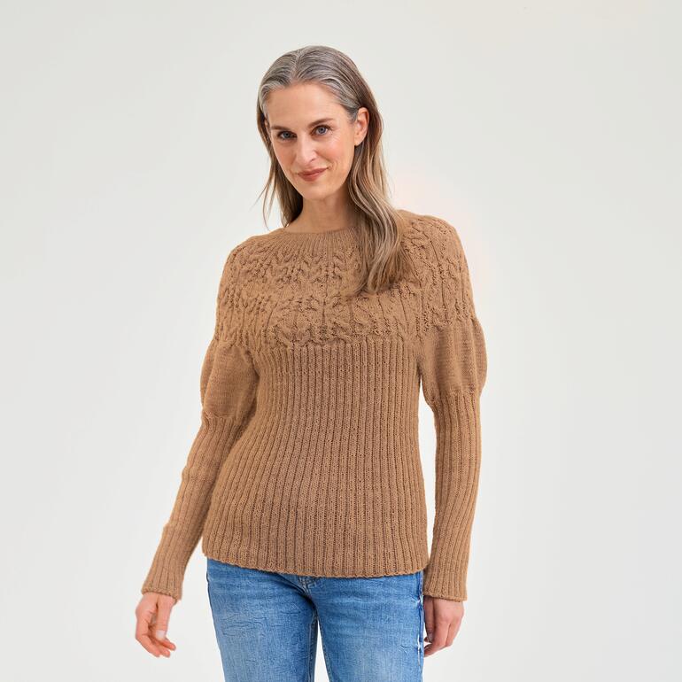 Frau in braunem strukturiertem Pullover lächelt freundlich.
