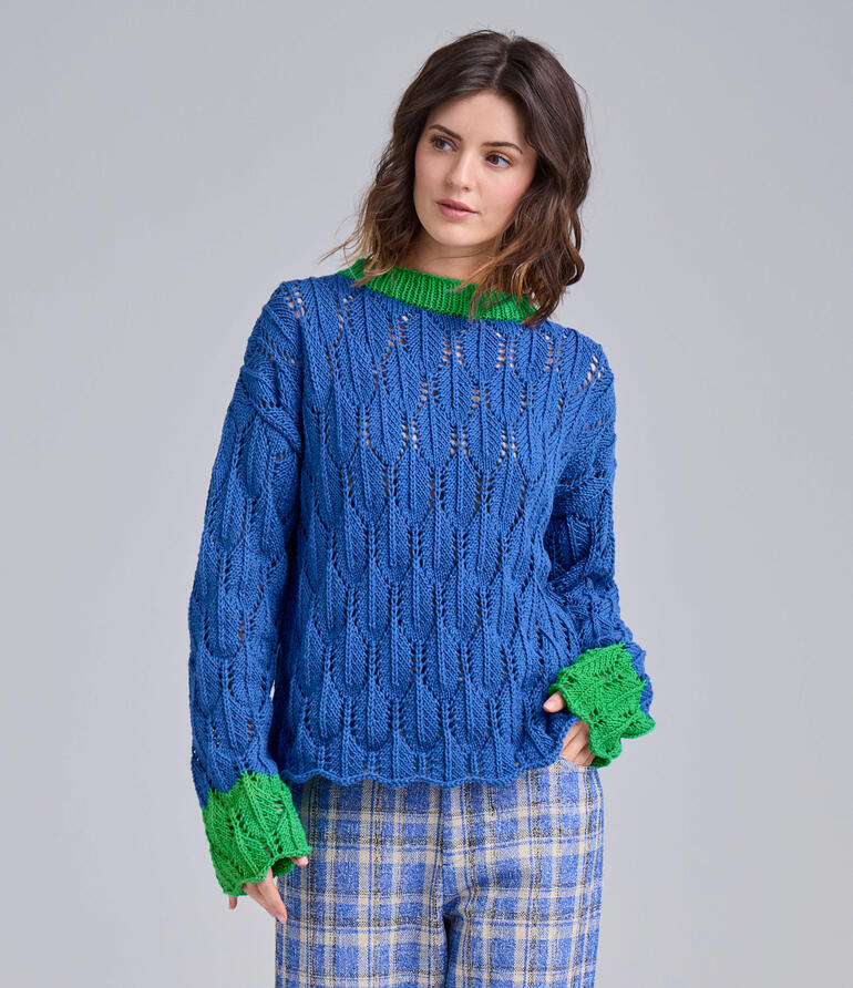 Frau trägt blauen Pullover aus Cotonara vor grauem Hintergrund.