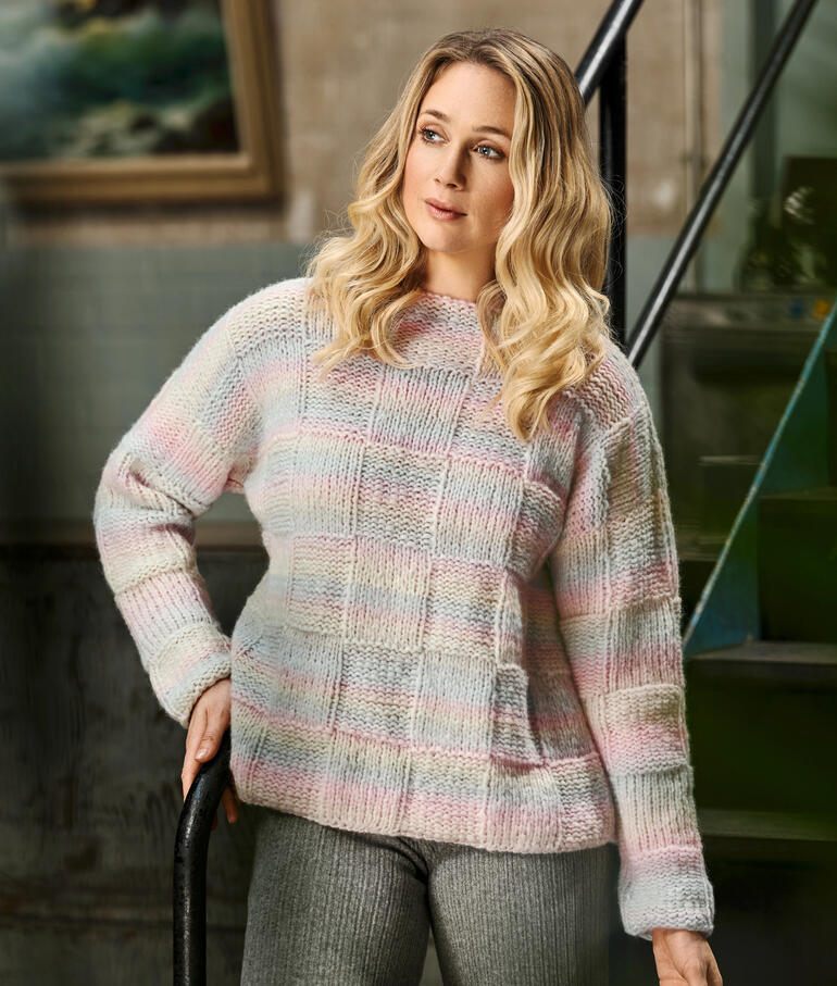 Frau trägt einen sanften, gestreiften Pullover in Pastellfarben.