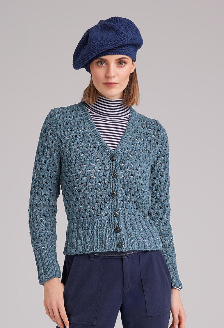 Frau in gestrickter Jacke aus Punktino mit stilvollem Hut.