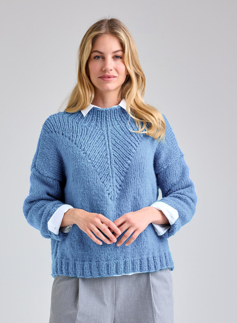 Frau trägt einen blauen Pullover aus NewWool mit V-Ausschnitt.